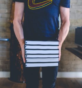 man carrying stacks of books